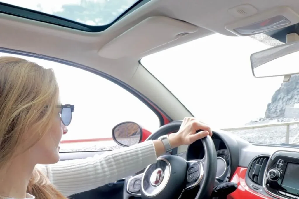 Woman driving a RotaMadeira rental car along Madeira's scenic coast